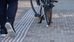 Iemand loopt met een taststok en raakt een geparkeerde fiets